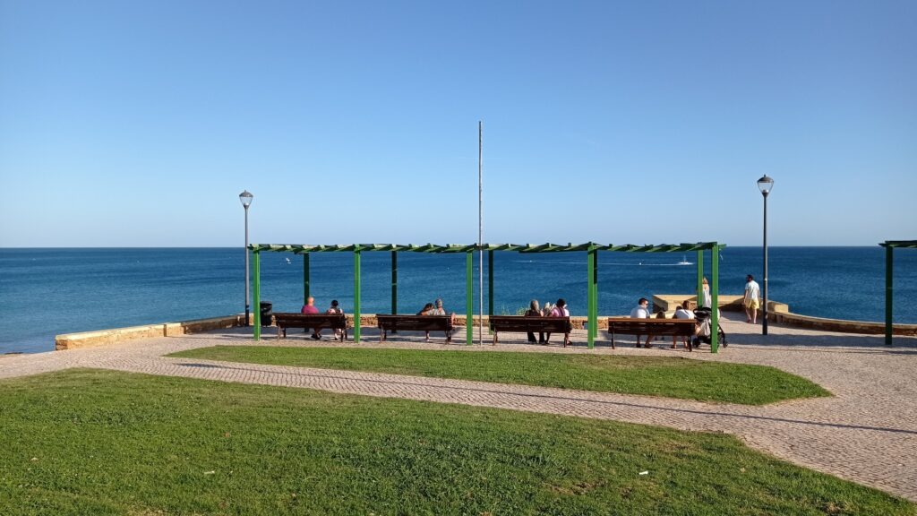 Trávník a altánek s lavičkami s výhledem na tyrkysové moře