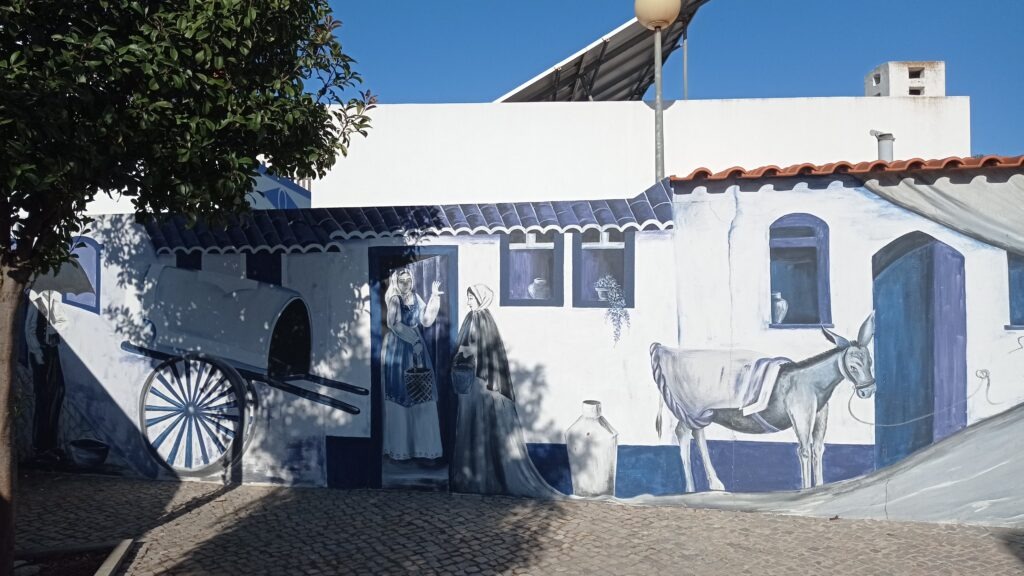 street art kdy je na fasádě domu modrobílá malba s lidmi, oknem a oslíkem