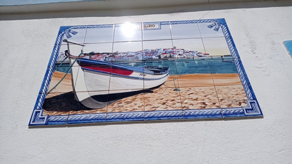 Moizaika z kachlíků na kterých je loď na břehu moře