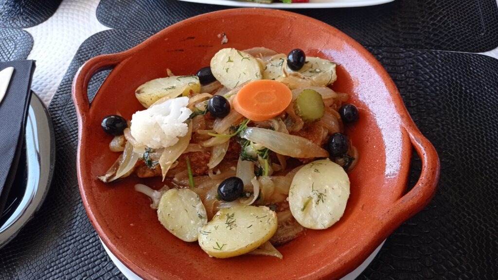 Oranžový hluboký talíř s rybou, bramborami, olivami, kolečkem mrkve