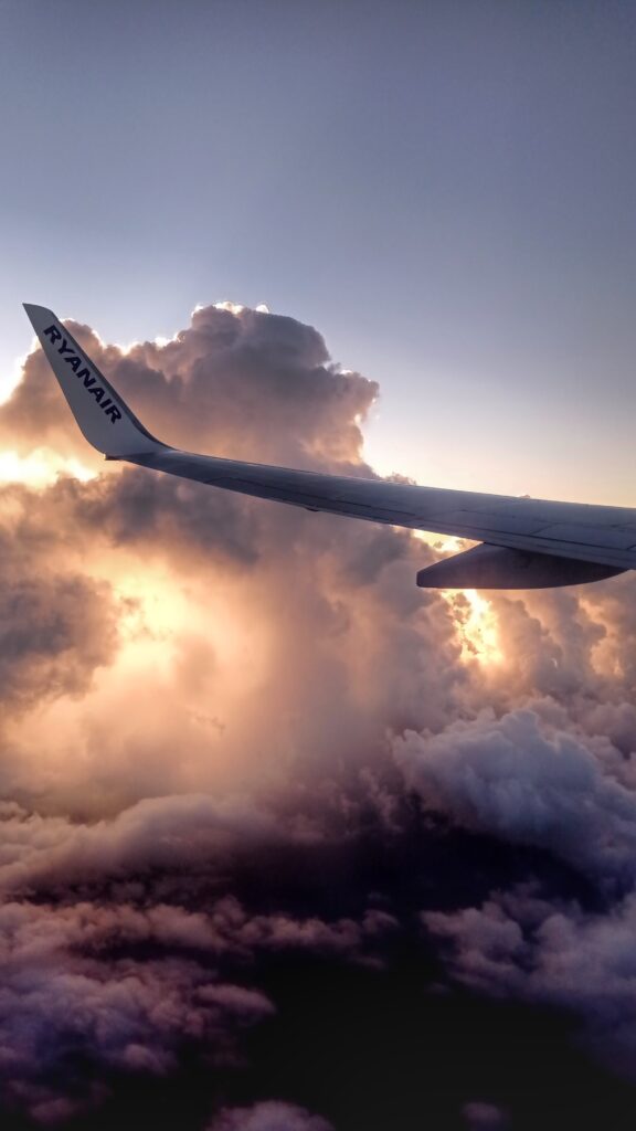Křídlo letadla a mraky kterými prosvítá slunce