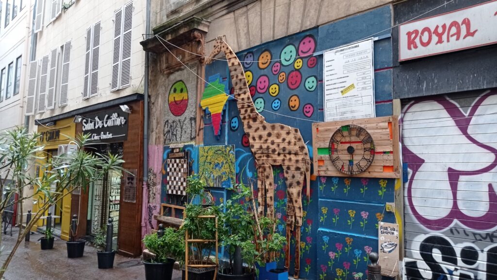 Malebná ulička s barevnou výzdobou, kde je žirafa a smajlíci