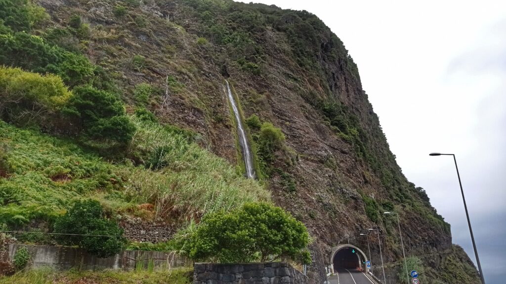 silnice s tunelem pod skálou ze které padá vodopád