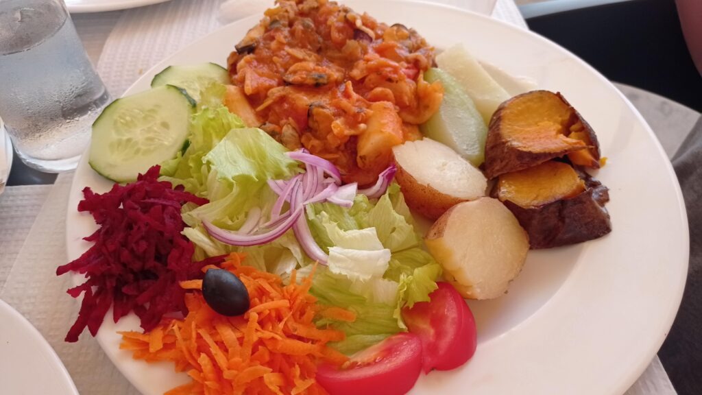 Bílý talíř s barmbory, batáty, strouhanou mrkví, řepou, kousky rajčete, salát okurka