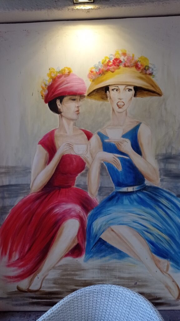 obraz s dvěma dámami, jedna v červených šatech, druhá v modrých šatech