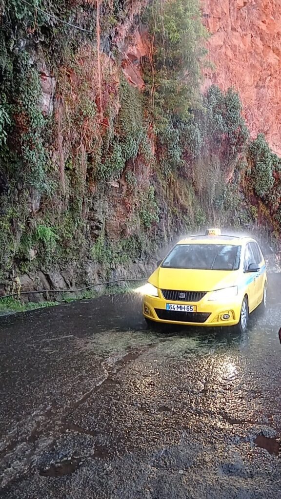 Vodopád dopadající na silnici a pod ním jedoucí žluté auto