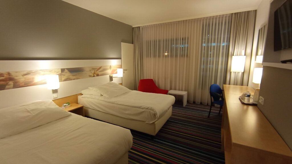 hotelový pokoj s dvěma postelemi a červeným křeslem