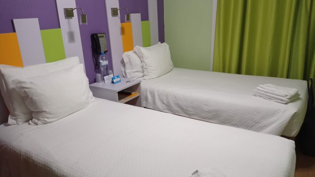 pokoj s fialovou stěnou a dvěma jednolůžkovými postelemi