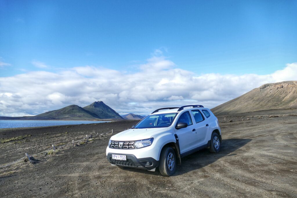 Bílé auto SUV uprostřed hor na Islandu