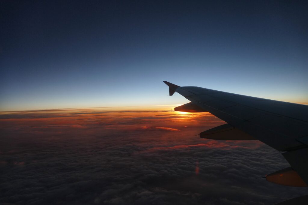 Výhled z letadla na západ slunce a křídlo letadla