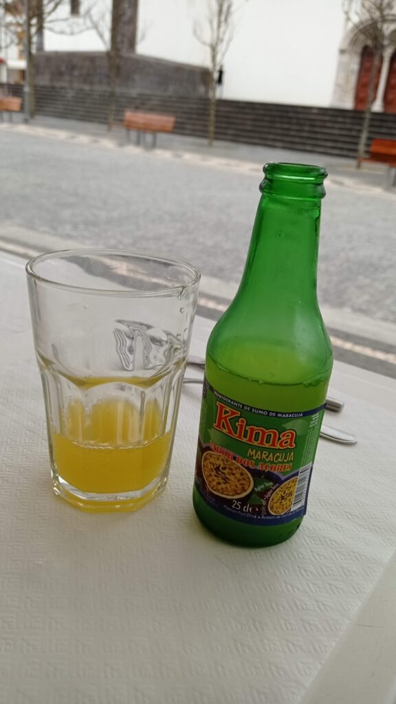 zelená lahev s limonádou Kima maracuja a poloprázdná sklenice