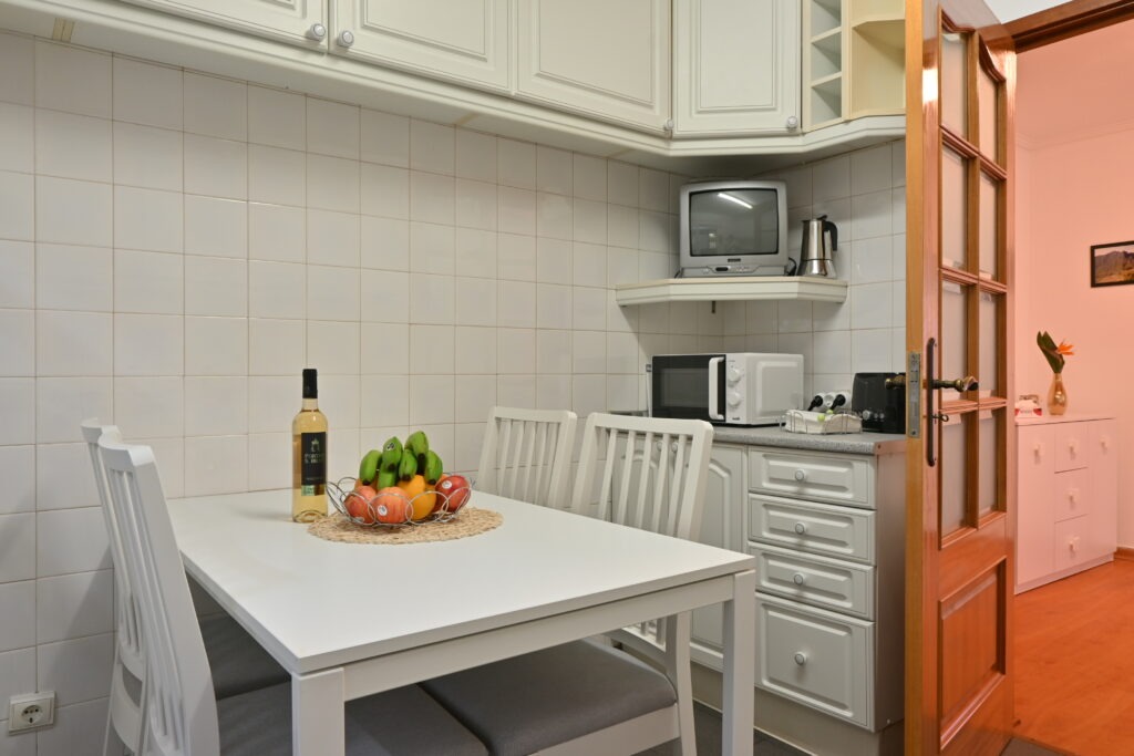 Kuchyň s židlemi a stolem na kterém leží ovoce a víno