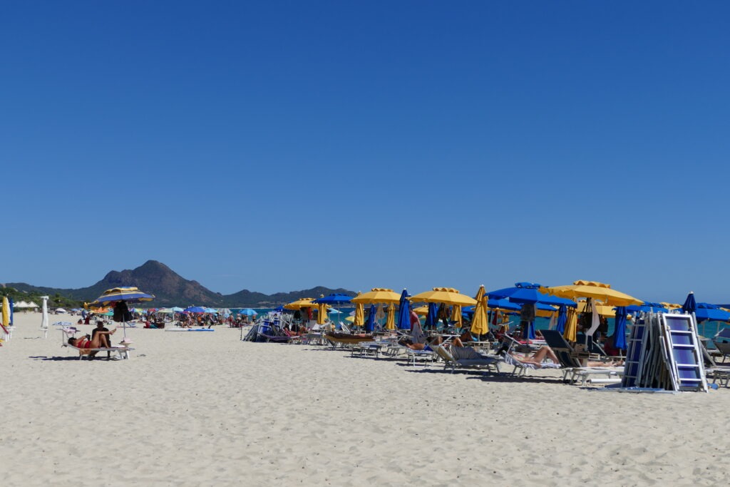 Písečná pláž se žlutými a modrými slunečníky