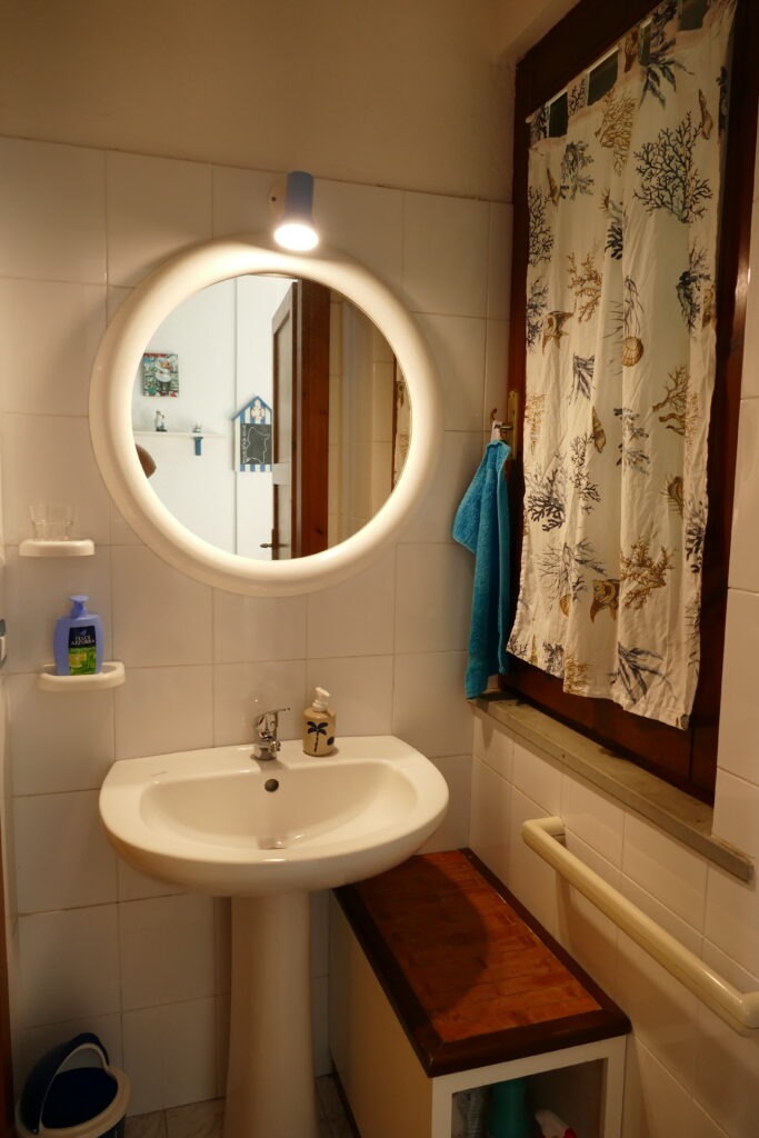 Koupelna s umyvadlem a kulatým zrcadlem