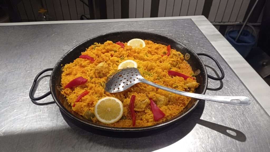 Paella - pánev s barevnou rýží, paprikou a plátky citrónu