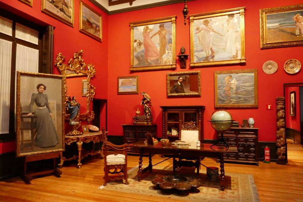 Pokoj se starožitným nábytkem a červená stěna s obrazy