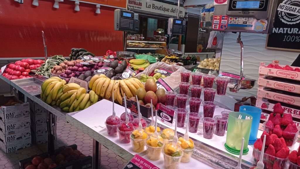 Stánek na tržnici s ovocem a kelímky se smoothie