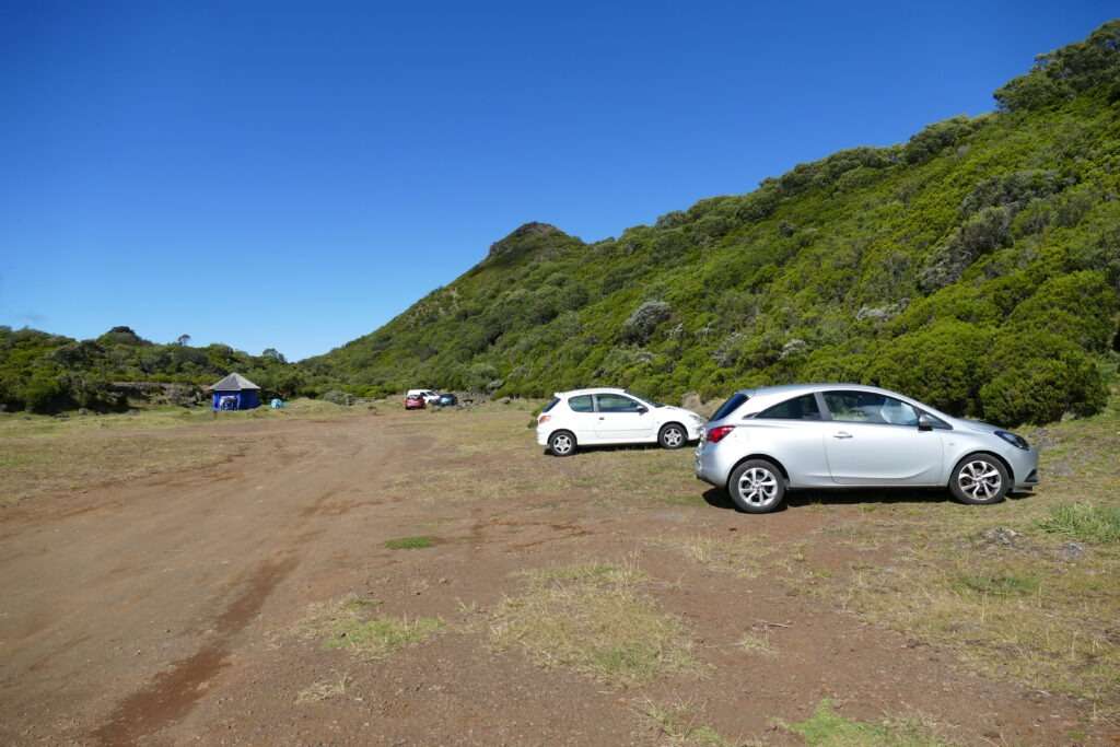 Parkoviště s několika auty a pohled na kopce