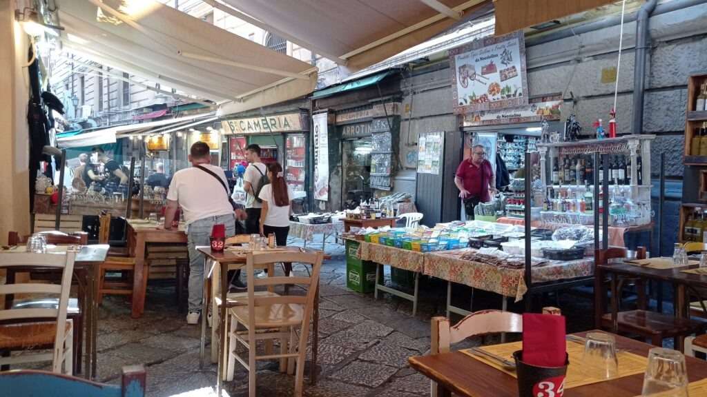 Ulička v Palermu s venkovním posezením restaurace