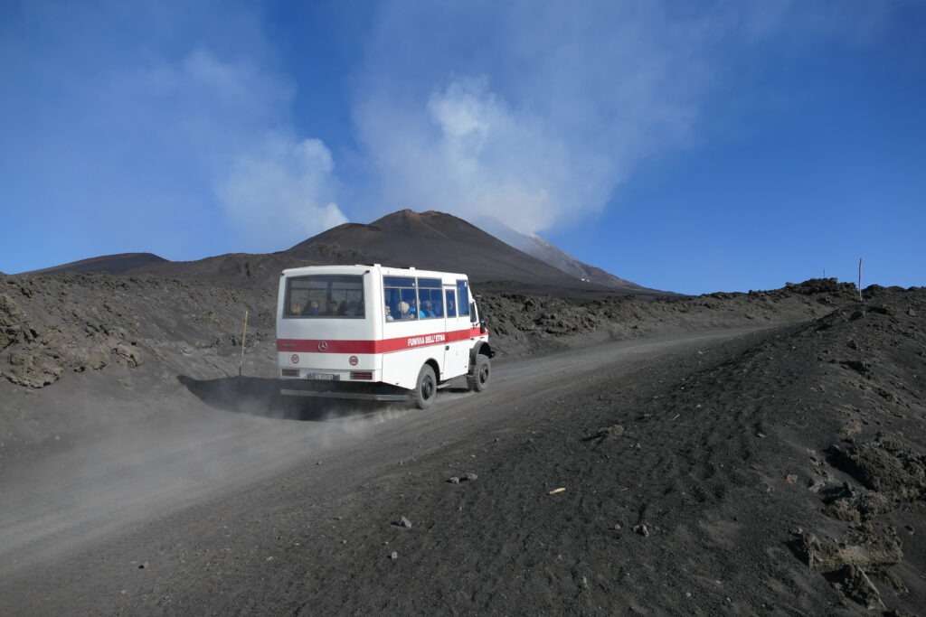 Minibus jedoucí po široké prašné cestě k sopce