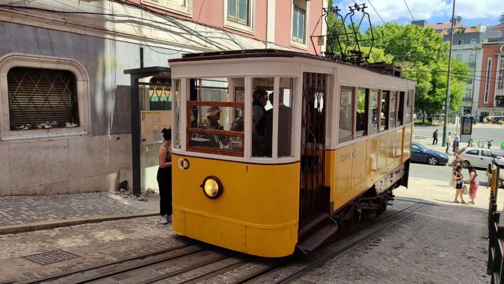 Žlutá tramvaj číslo 28 projíždějící úzkými ulicemi Lisabonu