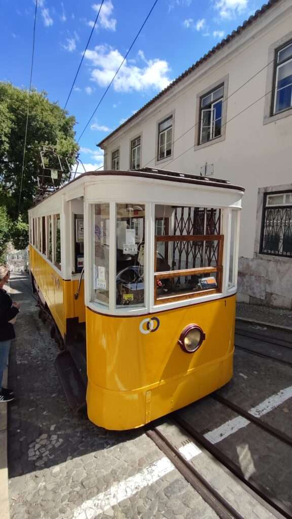 Žlutá tramvaj 28E zastavující ve staré čtvrti Lisabonu