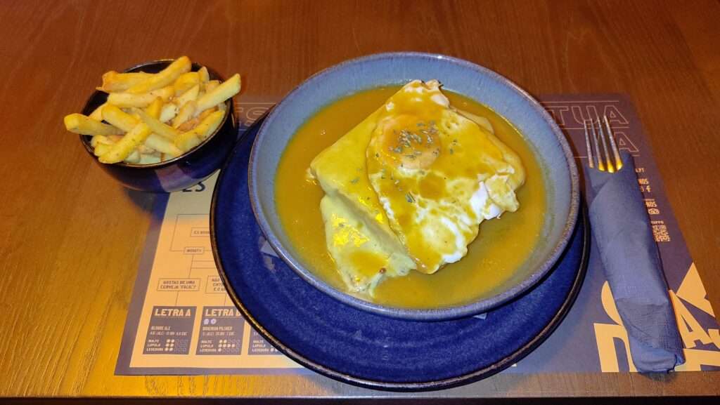 Francesinha - typické portugalské jídlo ze sendviče, omáčky a sýra s vajíčkem