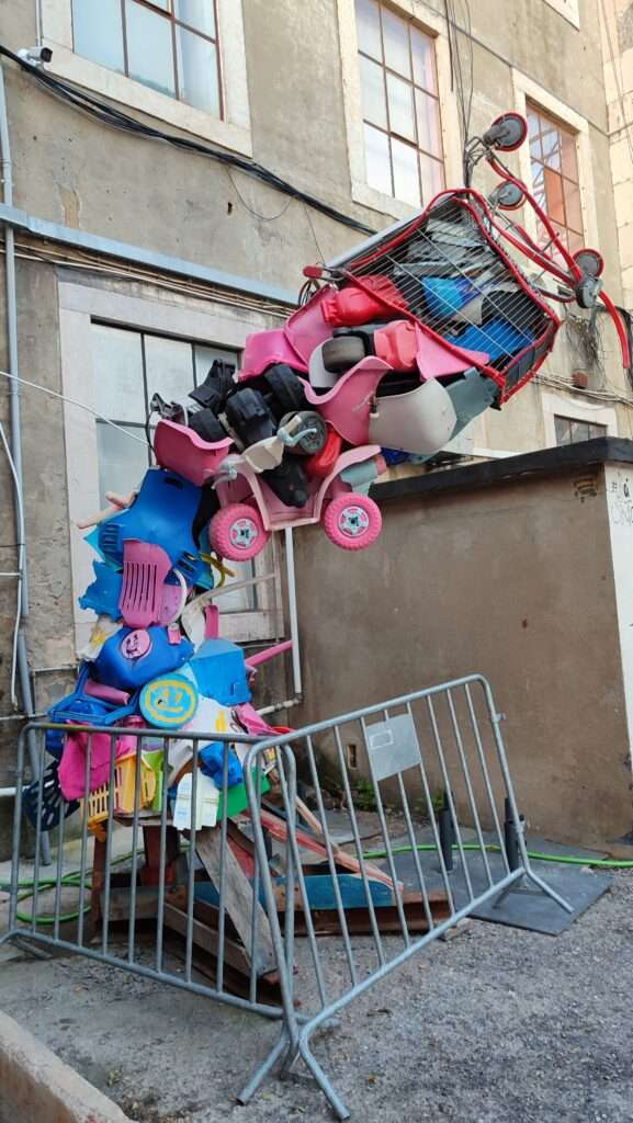 Street art s barevnými věcmi vyskládané do výšky a nahnuté
