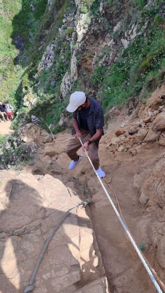 Turista šplhající po skalní stezce v přírodní oblasti