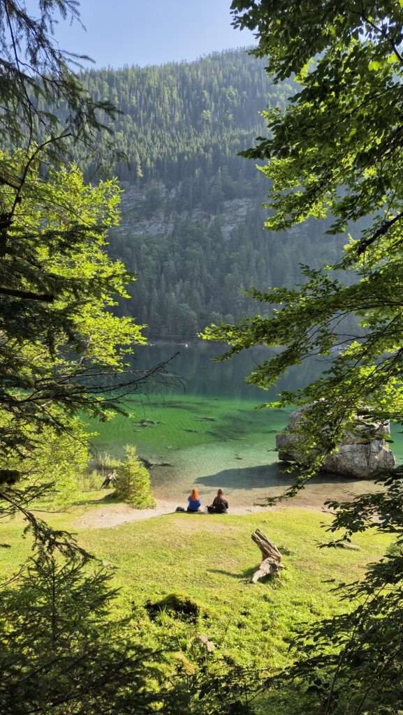 Turisté odpočívající u zeleného horského jezera