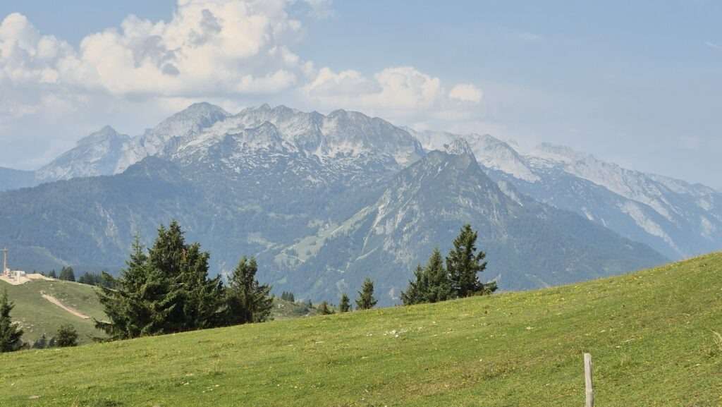 Alpská krajina se zelenými pastvinami a horami