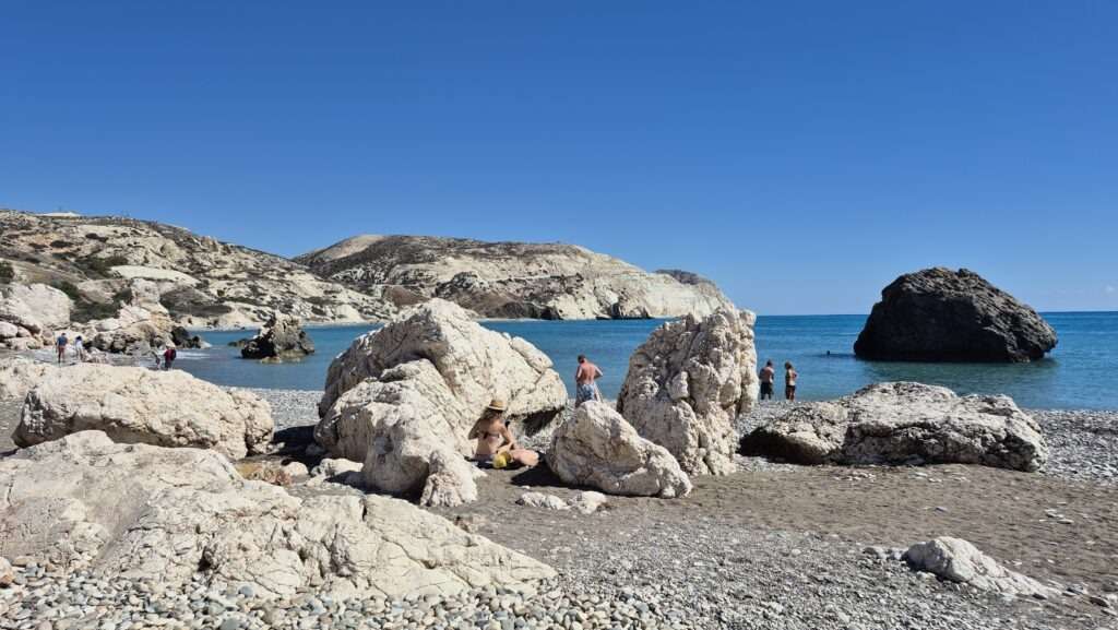 Pláž Petra tou Romiou s ikonickou Afroditinou skálou a tyrkysovým mořem.