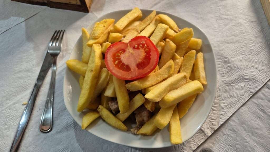 Picado - hranolky a pod ním maso a navrchu půlka rajčete